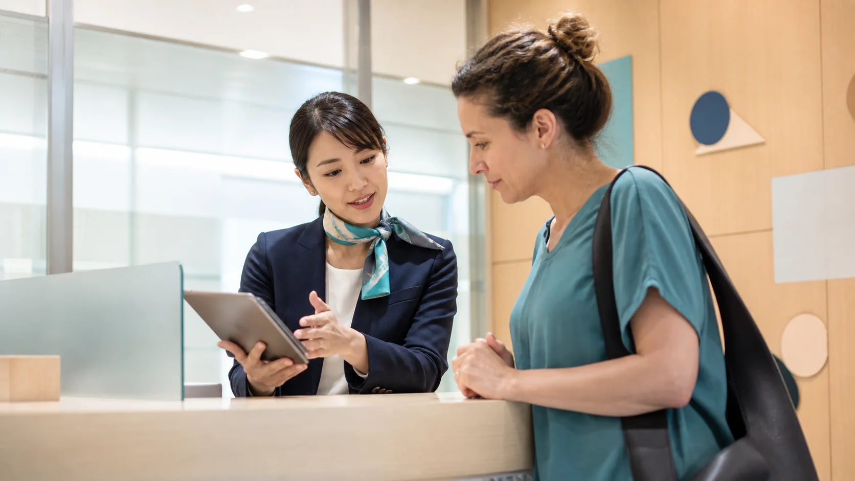 Hospital coordinator assisting an international patient at a reception desk